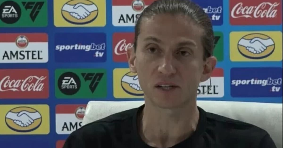 Técnico apoia atacante negro na lateral do estádio, torcida ao fundo com faixas contra o racismo, clima de solidariedade e denúncia