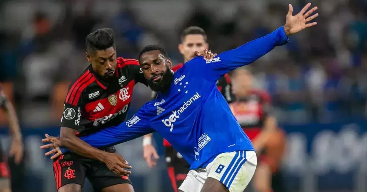 Três ex-companheiros se reencontram no gramado durante jogo, torcida ao fundo; cena viral com emoção e atmosfera de estádio.