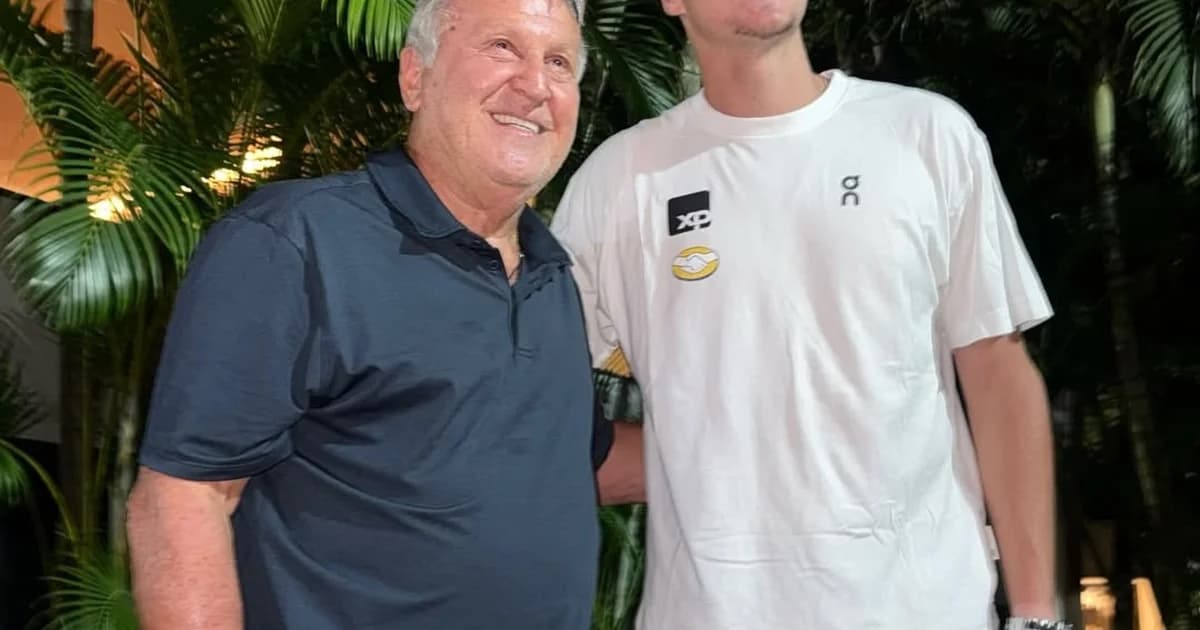 Tenista jovem posa com ex-jogador de futebol na quadra do Rio Open à noite, torcida e flashes ao fundo