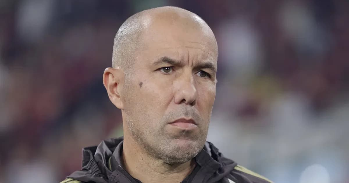 Treinador em silhueta na beira do campo, tensão da Libertadores entre Flamengo e Cruzeiro, torcida em vermelho e azul.