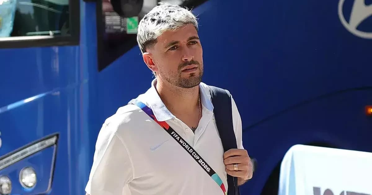Jogador uruguaio com punho esquerdo imobilizado no campo, médicos ao lado e estádio ao fundo; cena de lesão e cirurgia.