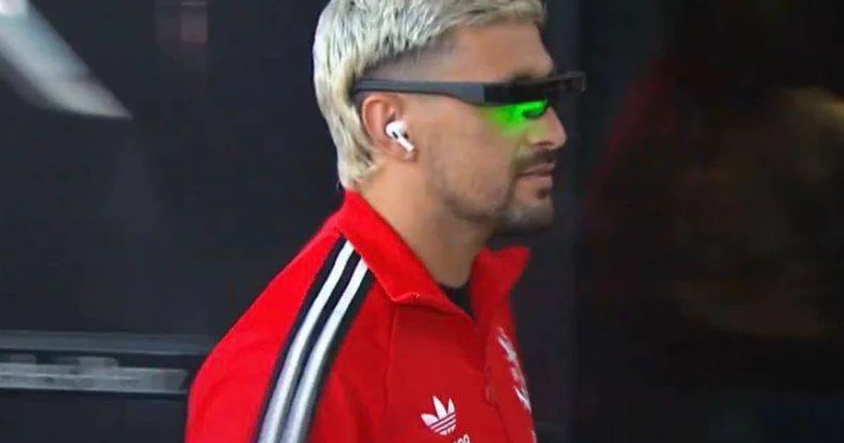 Jogador sem rosto usando aparelho de fototerapia Circádia com luz verde no estádio à noite; preparação para partida.