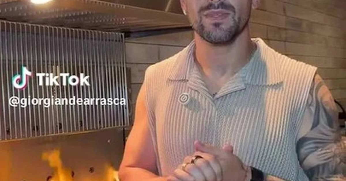 Grupo de jogadores no CT em churrasco ao ar livre, debatendo o ponto da carne ao redor de uma parrilla uruguaia.