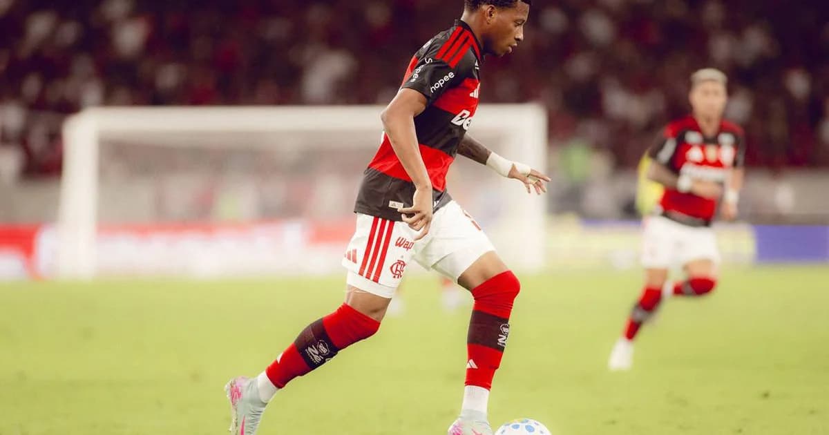 Jogador reintegrado cumprimentado por colegas na beira do campo, torcida em festa e placar 2 a 0 no Campeonato Brasileiro