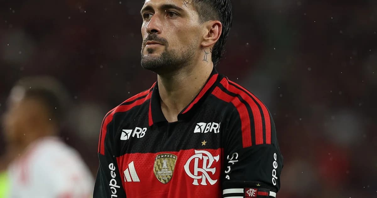 Arrascaeta comemora o gol 100 pelo Flamengo no Maracanã; torcida em vermelho e preto e telão com '100'.