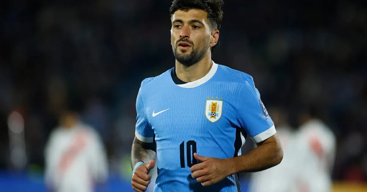 Meia uruguaio sem rosto, ombro enfaixado e fisioterapeuta ao lado, estádio ao fundo; tensão antes da estreia no Mundial