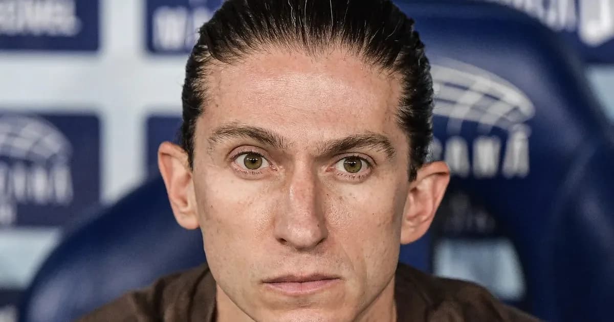 Treinador brasileiro favorito em silhueta diante de estádio alemão, torcida desfocada e clima de expectativa pelo Bayer Leverkusen
