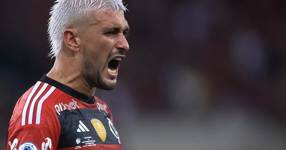 Trio de atacantes do Flamengo em ação na Recopa, estádio noturno em Buenos Aires com protestos ao fundo