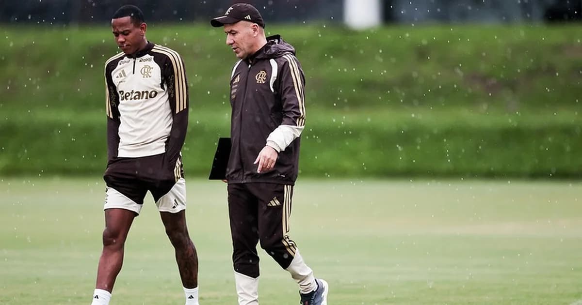 Técnico sem rosto analisando listas de atacantes em estádio ao anoitecer; camisas vermelhas e pretas, avaliação de atacantes Flamengo