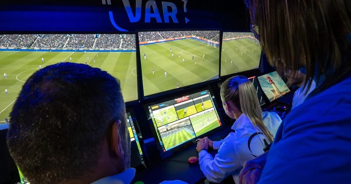 Ilustração editorial de estádio dividido entre torcidas em vermelho e verde, árbitro aponta e tela do VAR exibe gráficos e estatísticas.