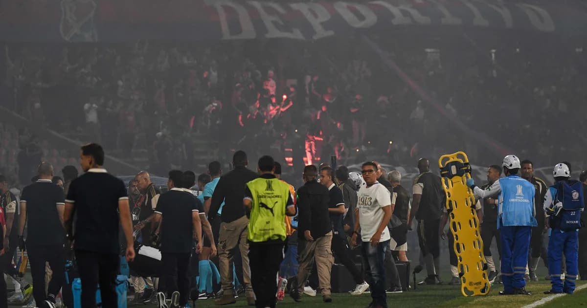Estádio em tumulto com fumaça e torcedores anônimos; partida Independiente Medellín x Flamengo cancelada
