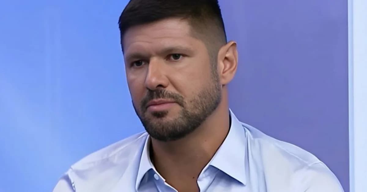 Ex-capitão no centro do estádio, bandeiras rubro-negras ao fundo e imprensa em primeiro plano, clima de expectativa e decisão.