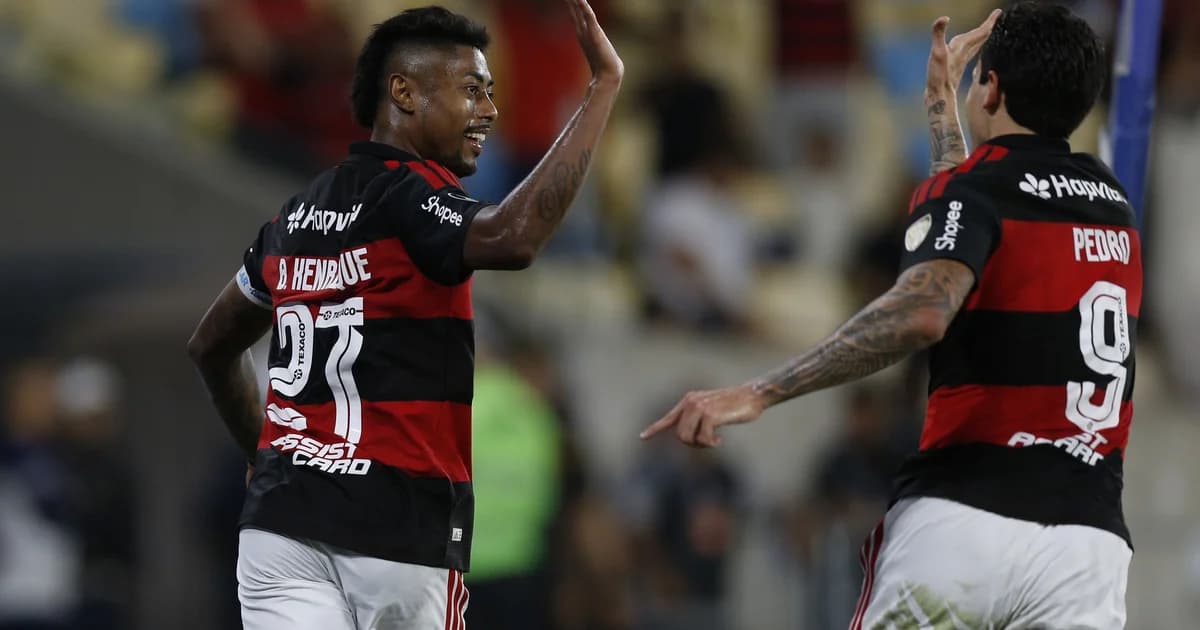 Torcida no Maracanã e jogadores do Flamengo em vermelho e preto comemoram vitória por 3 a 0 na Libertadores