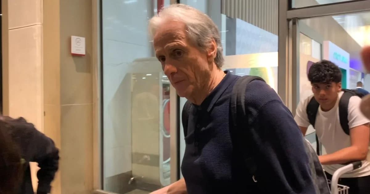 Treinador anônimo chegando ao Maracanã: silhueta no túnel, torcida em vermelho e preto nas arquibancadas e campo ao fundo