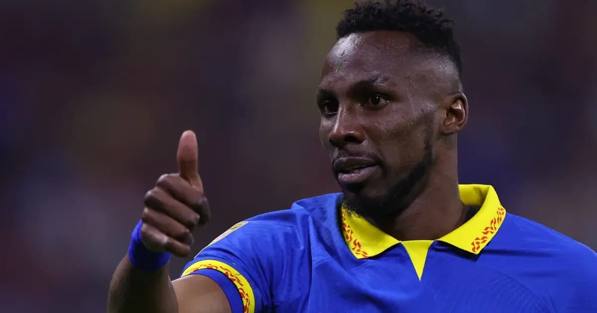 Atacante sem rosto comemora gol inaugural da Copa em estádio lotado; torcida vibra, clima de interesse de clubes brasileiros.