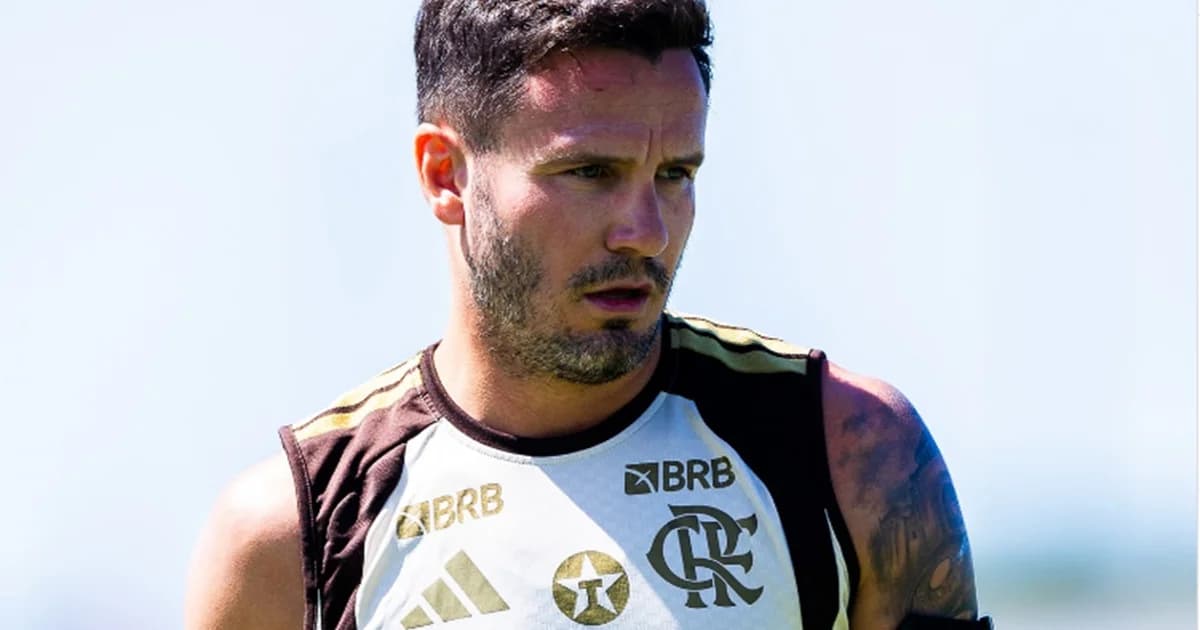 Meio-campista em reabilitação no gramado, tornozelo enfaixado, staff médico e técnico observando o retorno cauteloso do clube