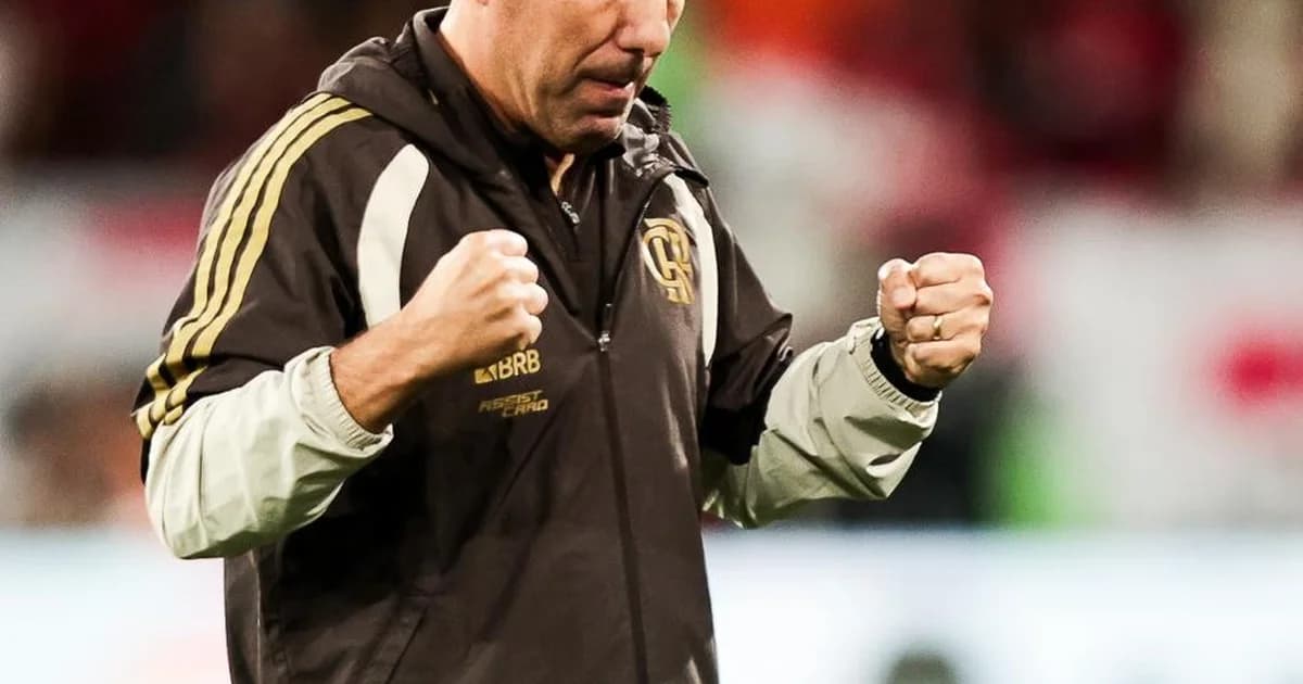 Jogador em vermelho celebra dois gols em estádio lotado; placar 3 a 0, torcida vibrando e técnico observando no banco.