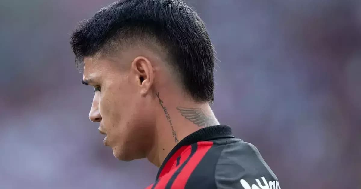 Atacante isolado no banco do Flamengo em estádio iluminado à noite, torcida desfocada e atmosfera tensa sobre futuro incerto