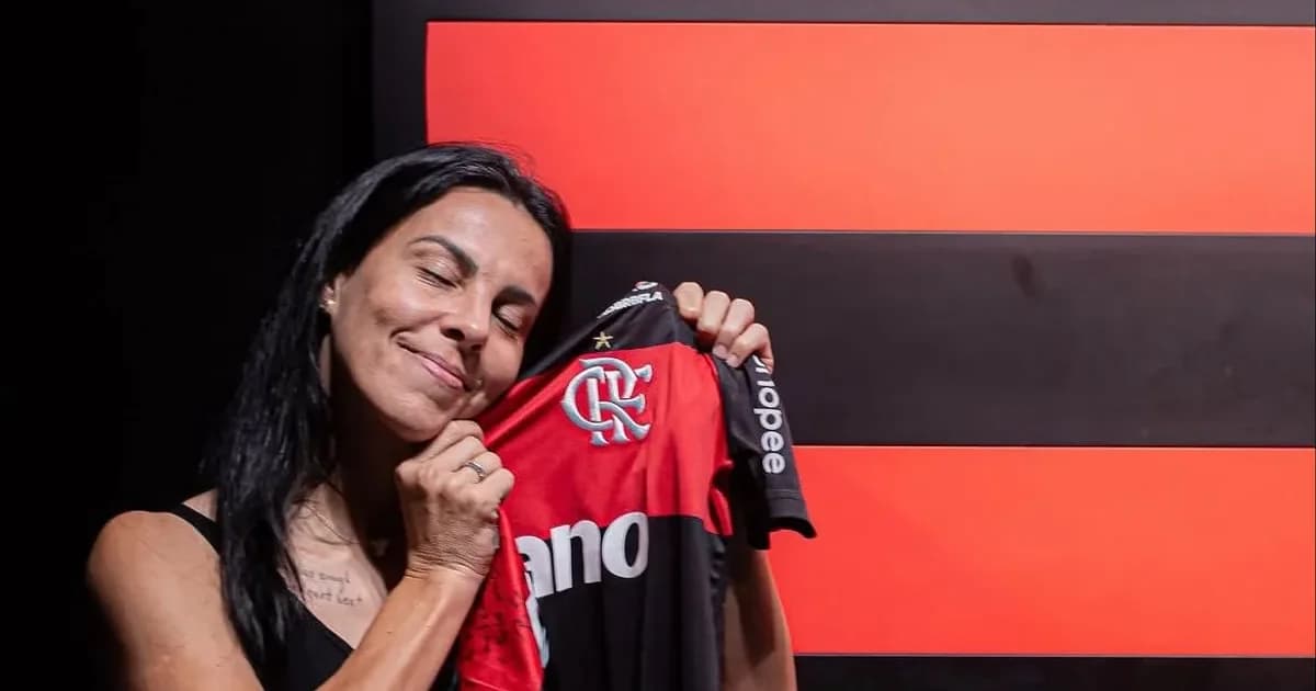 Jogadora de costas no centro do campo com camisa '100', homenagem no estádio, torcida com faixas e confetes, aposentadoria e 100 jogos pelo clube