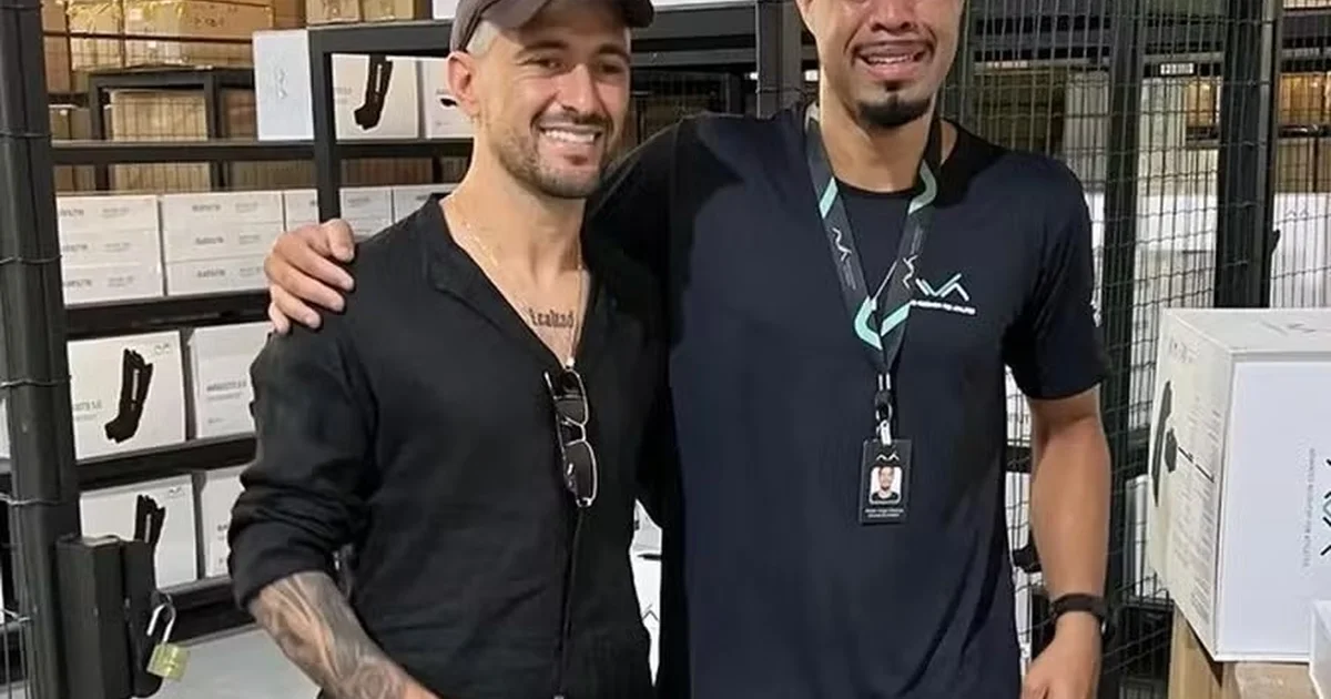 Torcedor emocionado ajoelhado chora ao encontrar jogador; colegas oferecem água, cena íntima de fã e atleta sem rostos identificáveis