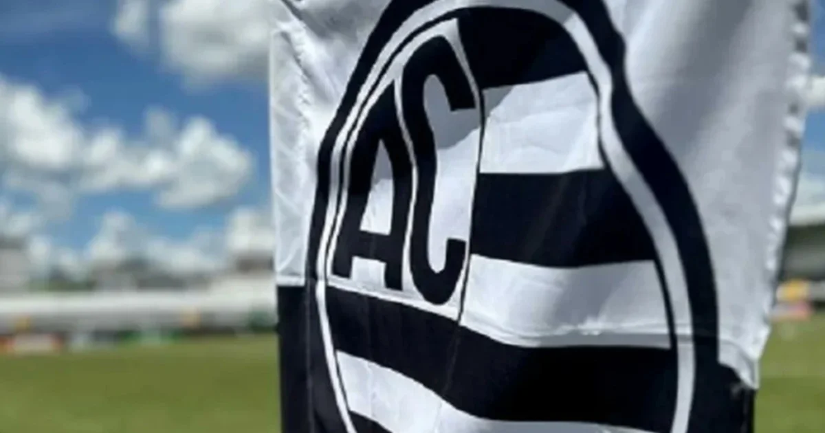 Ilustração editorial: treinador genérico de costas com prancheta no gramado, torcida lotada, luzes do estádio e placar ‘4 Mar - Copa do Brasil’