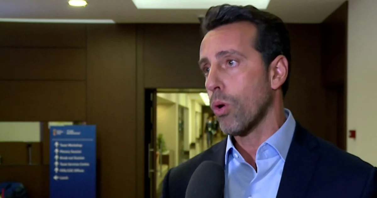 Silhueta de dirigente à beira do campo, torcida em vermelho e preto, referência a Edu Gaspar e Flamengo, clima de especulação.