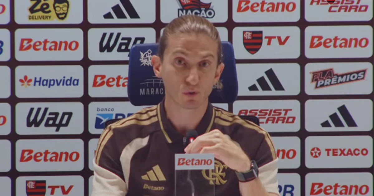 Treinador abraça atacante negro no gramado, torcida com faixas 'Racismo é crime', cena de apoio e pedido de punição no estádio