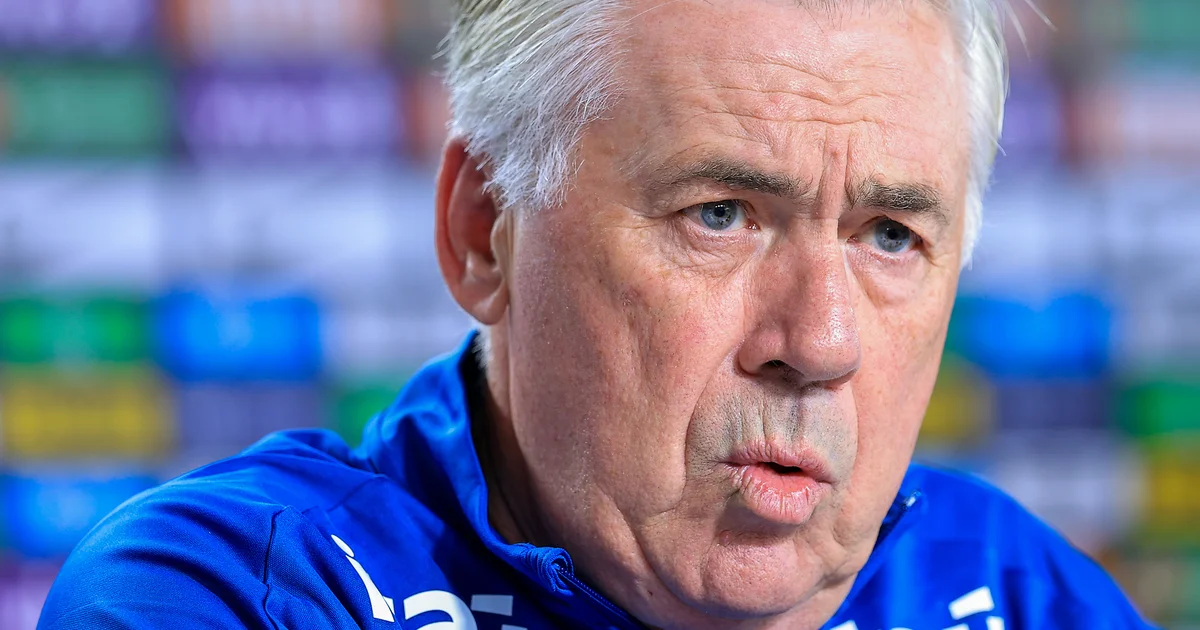 Lateral-esquerdo lesionado no gramado, médico atendendo, treinador com prancheta e estádio do Flamengo ao fundo, clima de preocupação