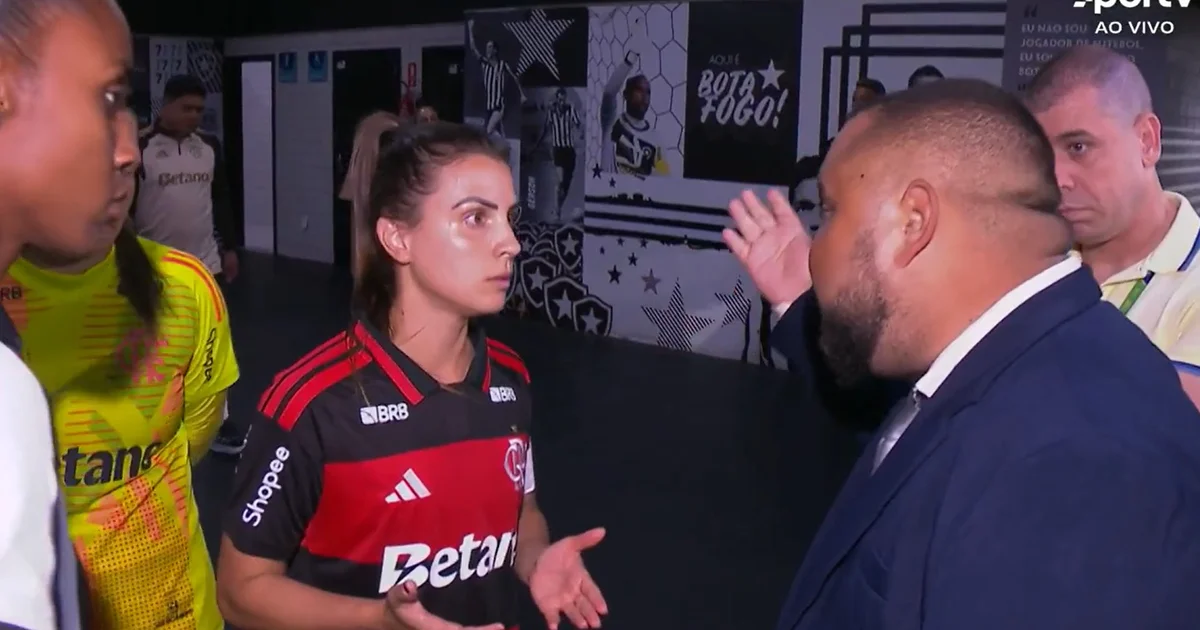 Capitãs conversam no gramado durante atraso das árbitras; placar mostra 'atraso 19:26' e torcida apreensiva.