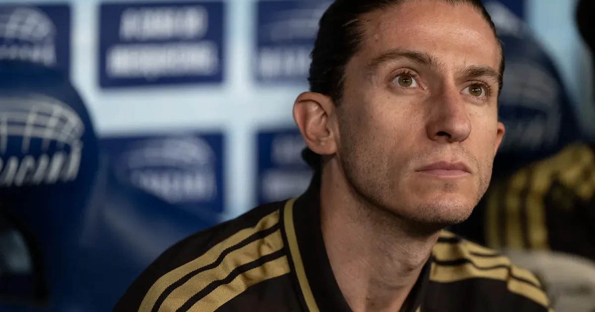 Atacante jovem sem rosto cabeceando em estádio, torcida desfocada em vermelho e preto; elementos abstratos de negociação e referência ao Flamengo