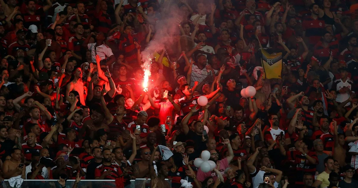 Multidão no Maracanã vestindo vermelho e preto, estádio quase lotado para jogo do Flamengo, torcida celebrando.