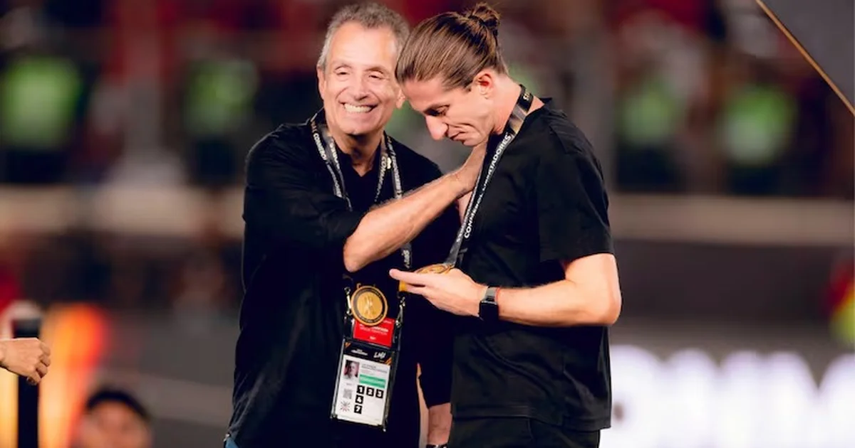 Técnico em reunião com diretoria, estádio ao fundo e torcida em vermelho e preto, clima de pressão no campeonato