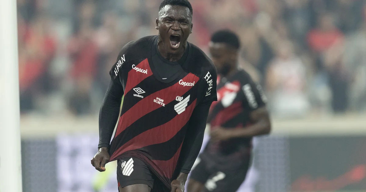 Ilustração de estádio com vaga de centroavante vazia, técnicos observam, cores vermelho e preto, clima tenso e tático