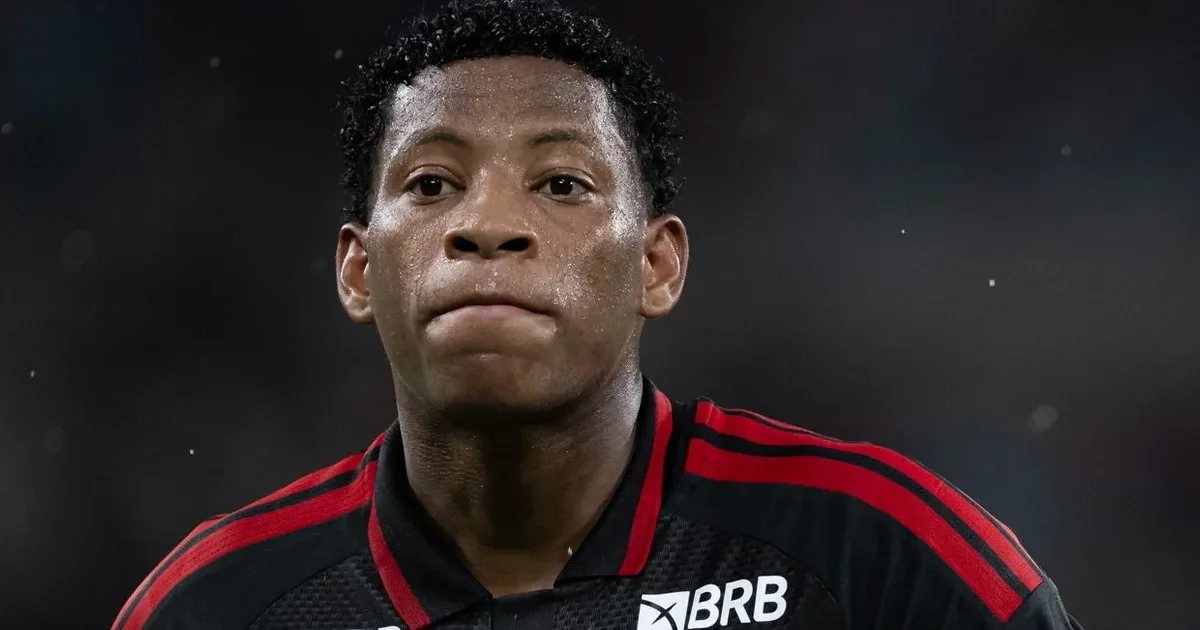 Treinador observa ponta em ação em estádio lotado com torcida em vermelho e preto, simbolizando venda do jogador do Flamengo e busca por substituto.