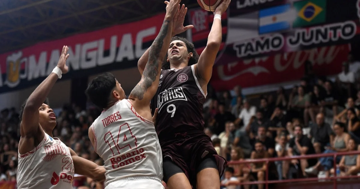 Faixas rubro‑negras do Flamengo nas arquibancadas de um jogo de basquete do Lanús, torcida e quadra iluminada