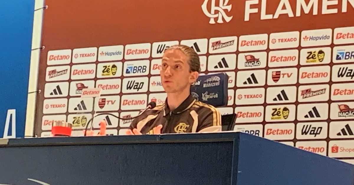 Treinador abraça atacante no campo em gesto de apoio após polêmica de racismo, torcida solidária ao fundo