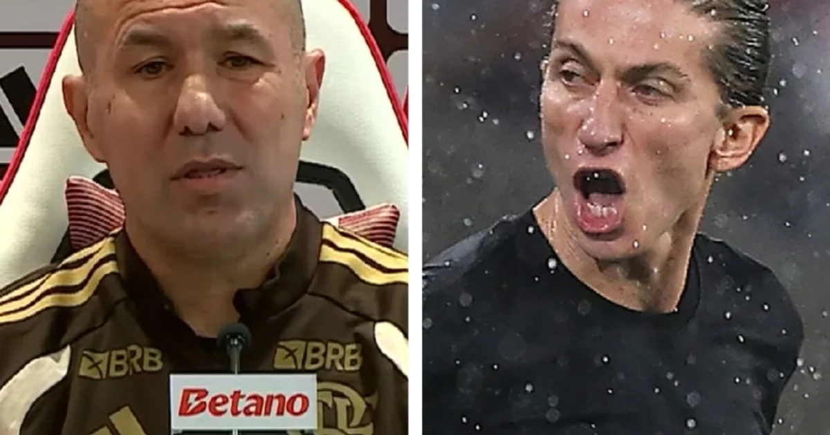 Treinador em coletiva no centro de treinamento do Flamengo, fala ao celular em gesto conciliador, torcida ao fundo e luz natural.