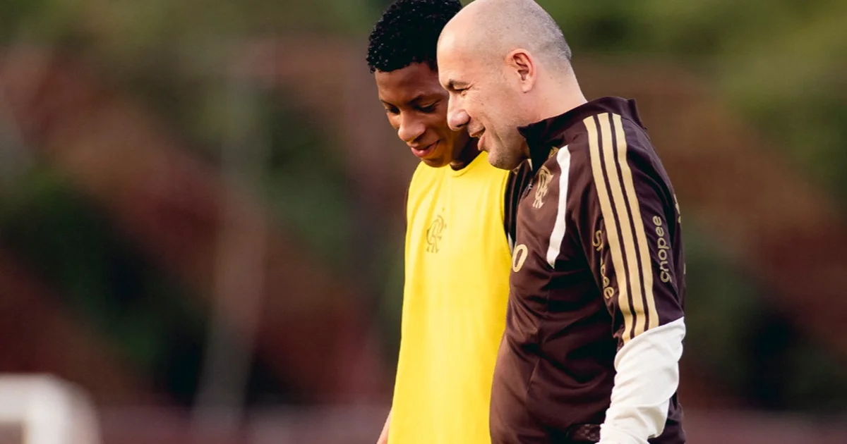 Treinador recém-chegado comanda treino no Ninho do Urubu: elenco de coletes vermelho e preto no gramado, clima de foco e expectativa matinal