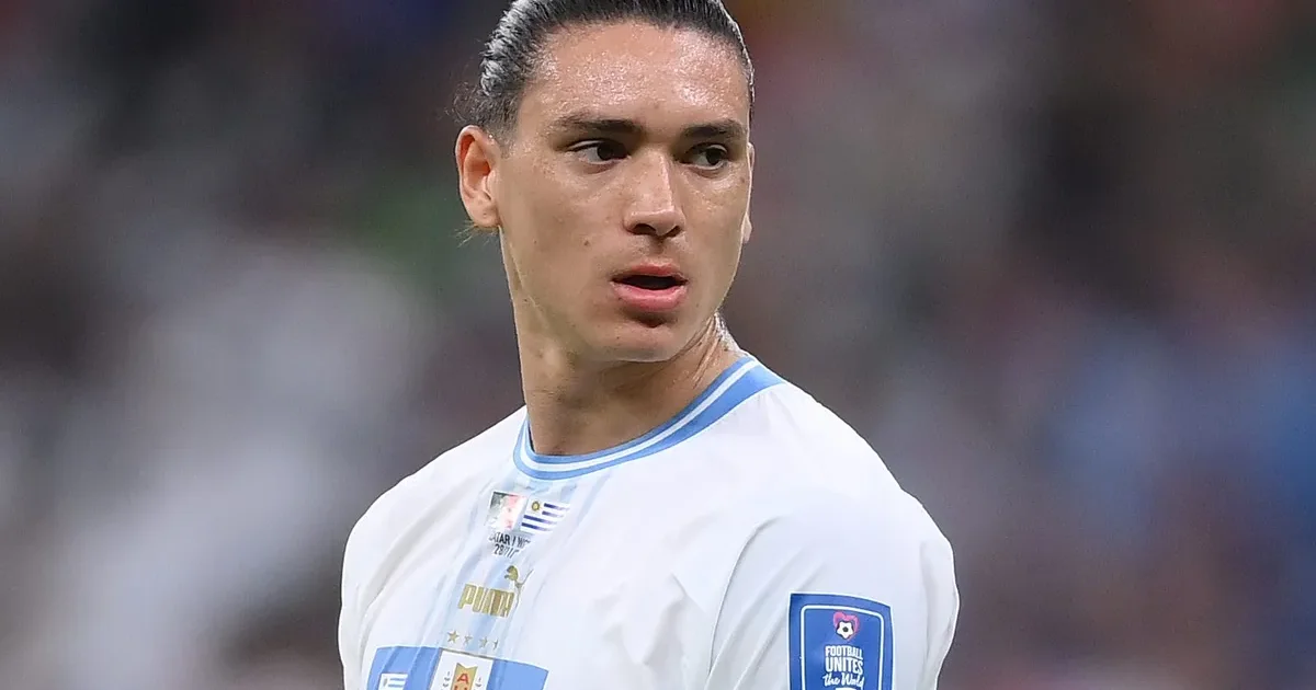 Ilustração editorial: estádio noturno com atacante alto de costas em camisa rubro-negra sem escudo, placar 0-1 e torcida tensa