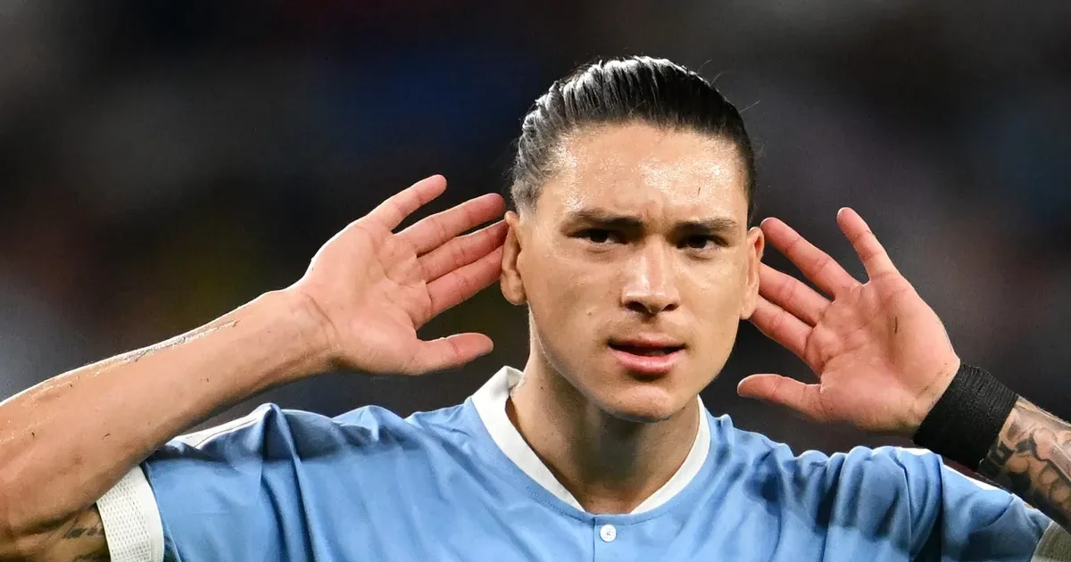 Estádio lotado, atacante genérico de vermelho e preto cabeceia em lance tenso — ilustração sobre Flamengo monitorando centroavante