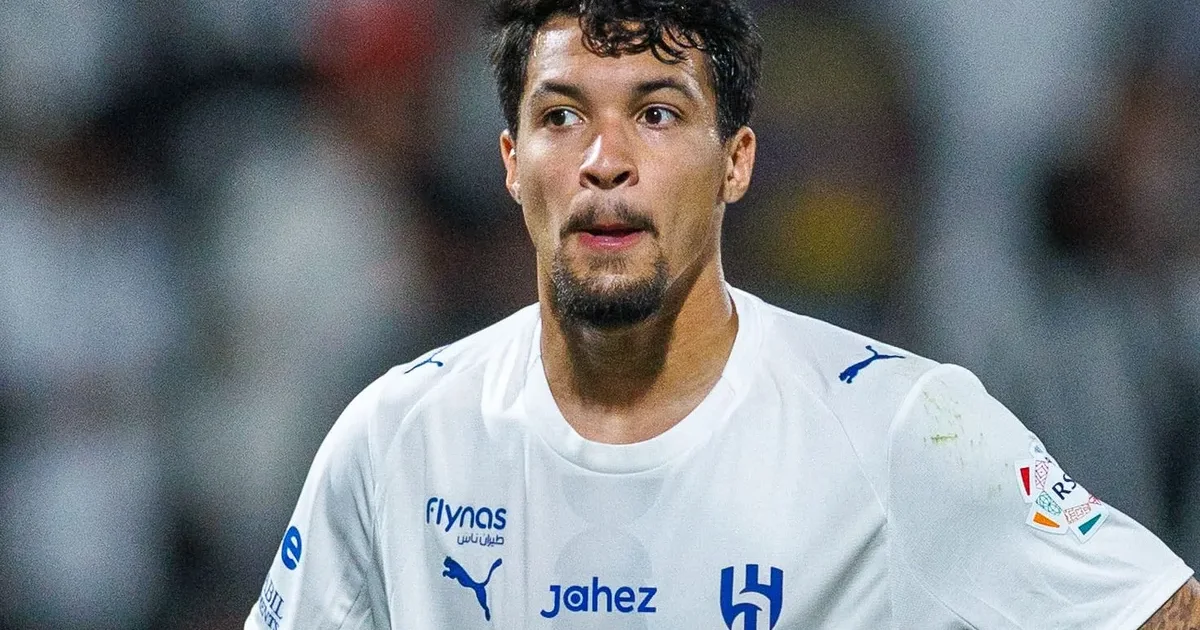 Atacante observado por scout em estádio iluminado, contratos espalhados e horizonte com fumaça; Flamengo monitora Marcos Leonardo no mercado.