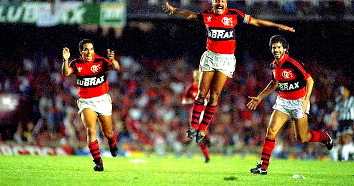 Ídolo do Flamengo em noite de autógrafos no Casa Shopping, Barra da Tijuca, com fãs de vermelho e preto e pilha do livro comemorativo sendo assinada