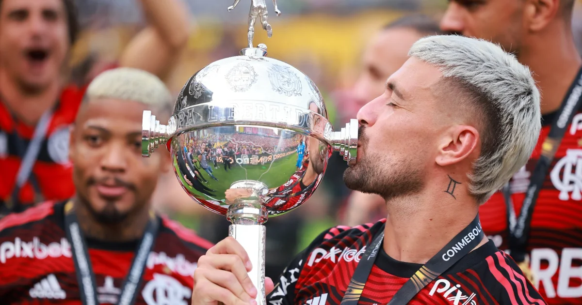 Estádio Nilton Santos à noite: torcida em vermelho celebra troféu continental estilizado; provocação nas redes entre Flamengo e Botafogo.