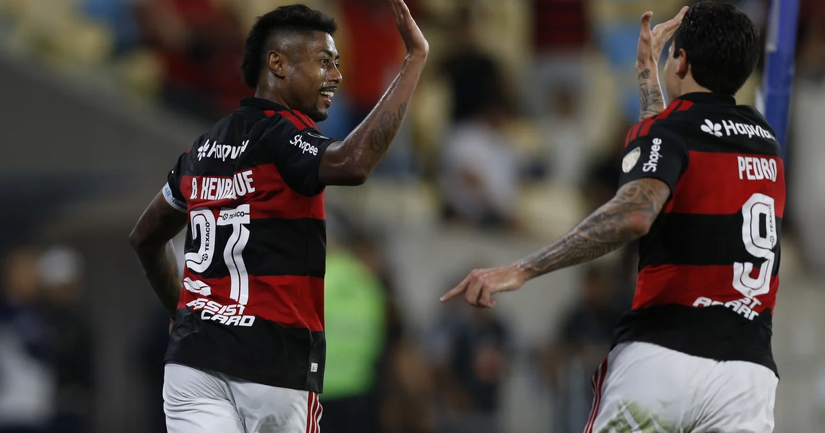 Torcida no Maracanã e jogadores do Flamengo em vermelho e preto comemoram vitória por 3 a 0 na Libertadores