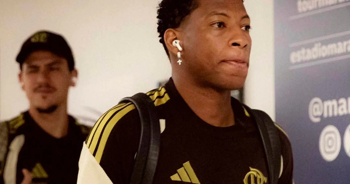 Estádio ao entardecer: jogador em silhueta, diretor hesitante e documentos de transferência no ar; tensão sobre decisão de clube brasileiro.