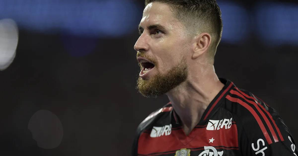 Capitão com braçadeira no gramado do Nilton Santos, torcida vibrando, cores rubro‑negras e comemoração da vitória.