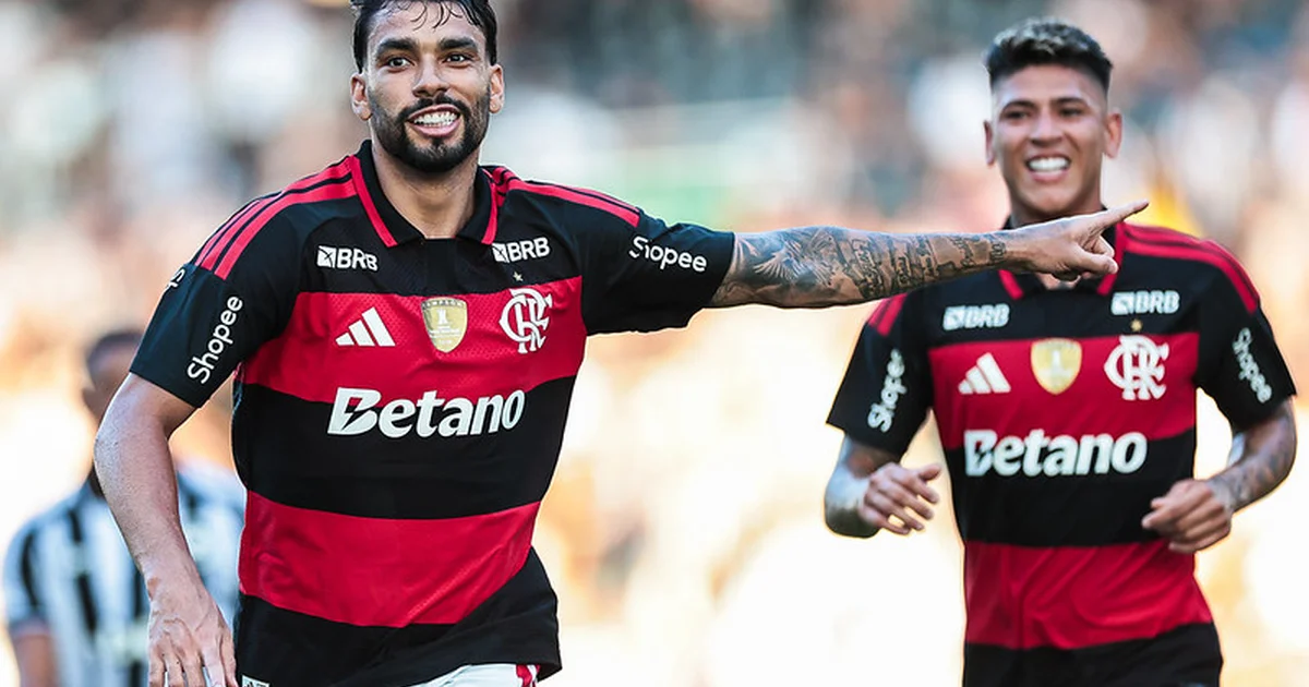 Meio-campista brasileiro retornando ao clube em estádio lotado, mentor orientando na lateral, torcida em vermelho e preto, clima de expectativa.