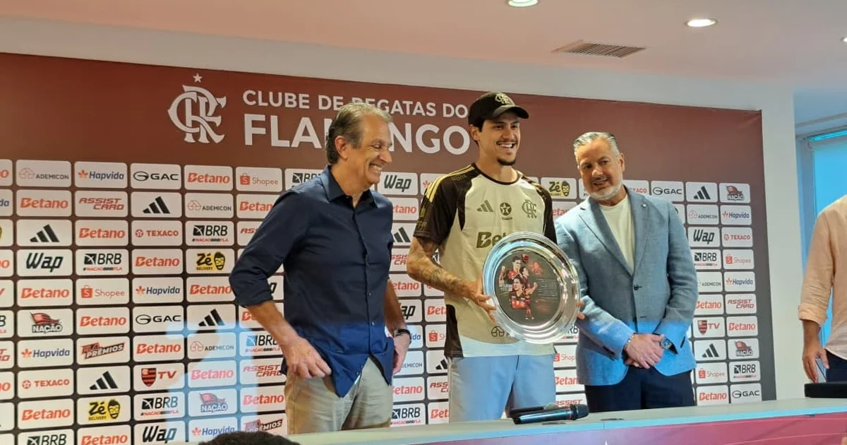 Atacante homenageado em treino recebendo placa, confetes e aplausos, cena de celebração pelos 163 gols pelo Flamengo.