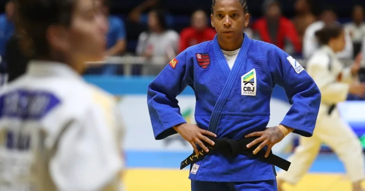 Atleta sem rosto deixa estádio ao pôr do sol, caminhando rumo a um centro esportivo comunitário na favela — retorno e esperança.