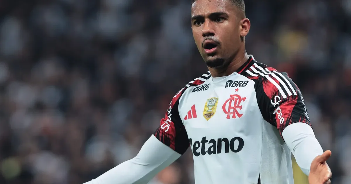 Samuel Lino no estádio do Flamengo, postura confiante em kit vermelho e preto, torcida ao fundo e clima de permanência.